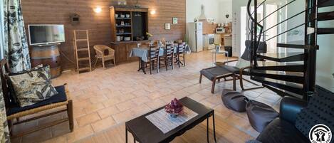 A spacious living area with a wooden ceiling, a dining set, and a modern staircase.