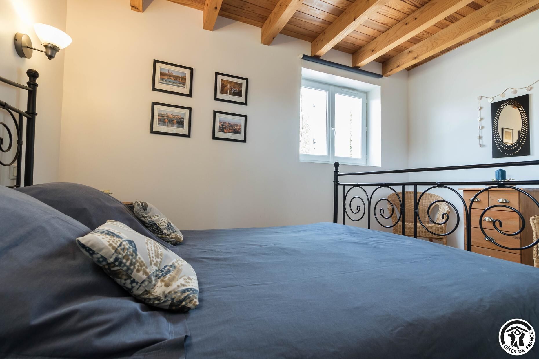 Une chambre à coucher avec un lit, une fenêtre et quatre tableaux encadrés accrochés au mur.
