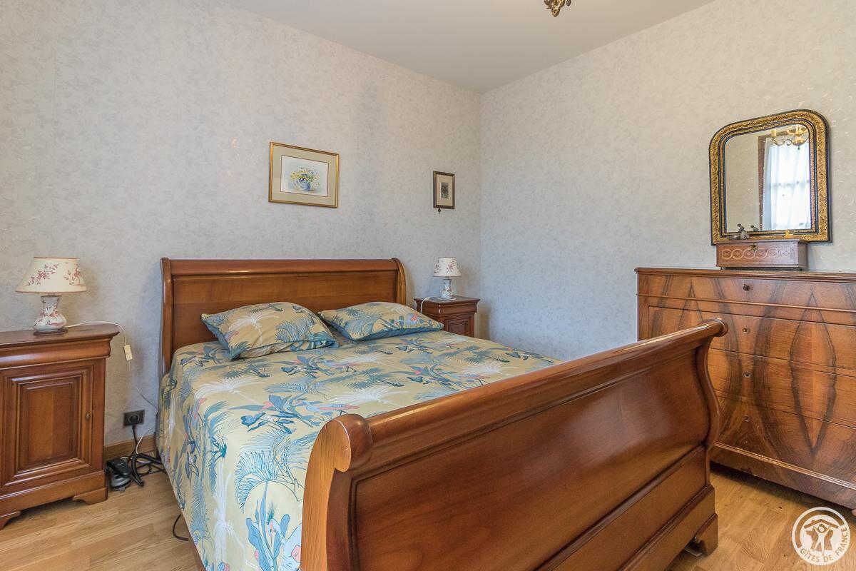 A bedroom with a wooden bed, a dresser, and a mirror.