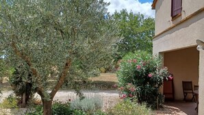 A garden with various plants and flowers, a tree, and a building with a window and a door. - Domaine de Blanconne (Léguevin)