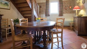 A rustic dining room with a wooden table, chairs, and a staircase. - Domaine de Blanconne (Léguevin)