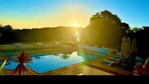 Piscina con vistas al atardecer, sillas de descanso y sombrillas.
