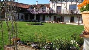 Un edificio tradicional con un patio interior, que cuenta con un césped cuidado y macizos de flores.