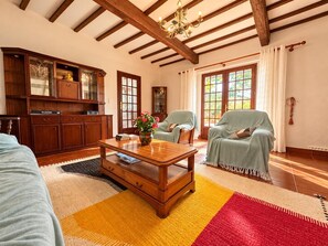 Ein Zimmer mit Holzmöbeln, einem Couchtisch und einem großen Fenster mit Vorhängen.