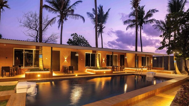 Un hotel moderno con piscina, asientos exteriores y palmeras.