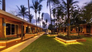 Un hotel con diseño moderno, que cuenta con un camino bien iluminado, espacios para sentarse al aire libre y un césped verde exuberante.