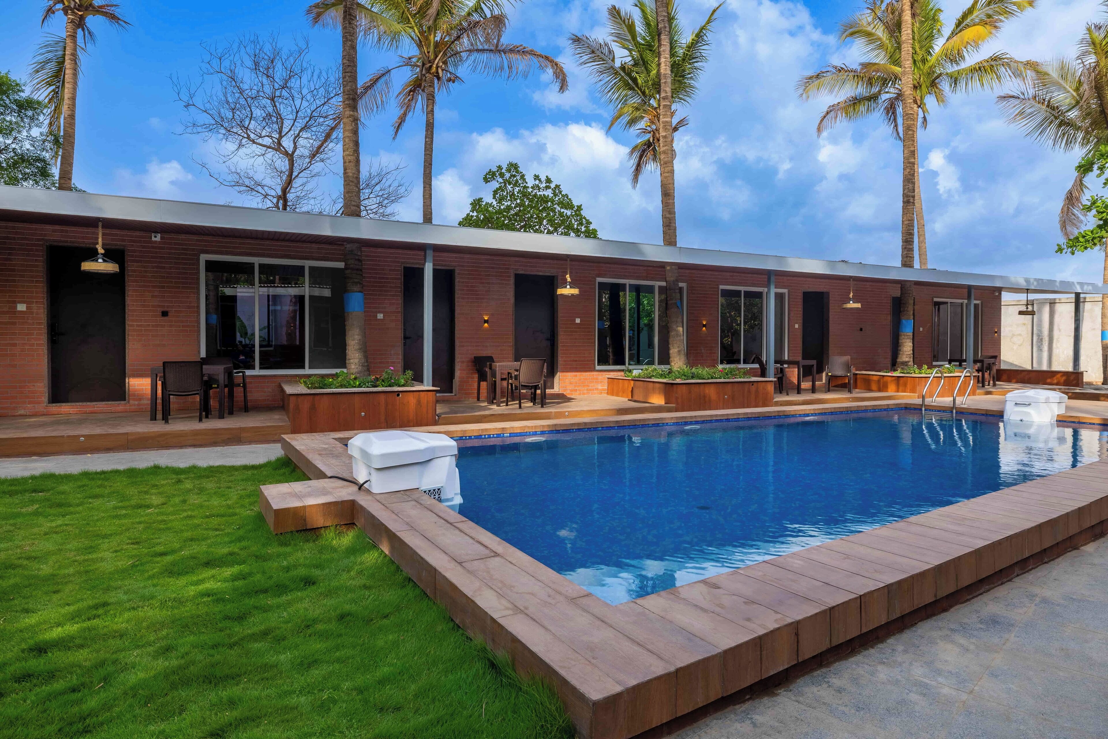 A modern house with a swimming pool, outdoor seating, and palm trees.