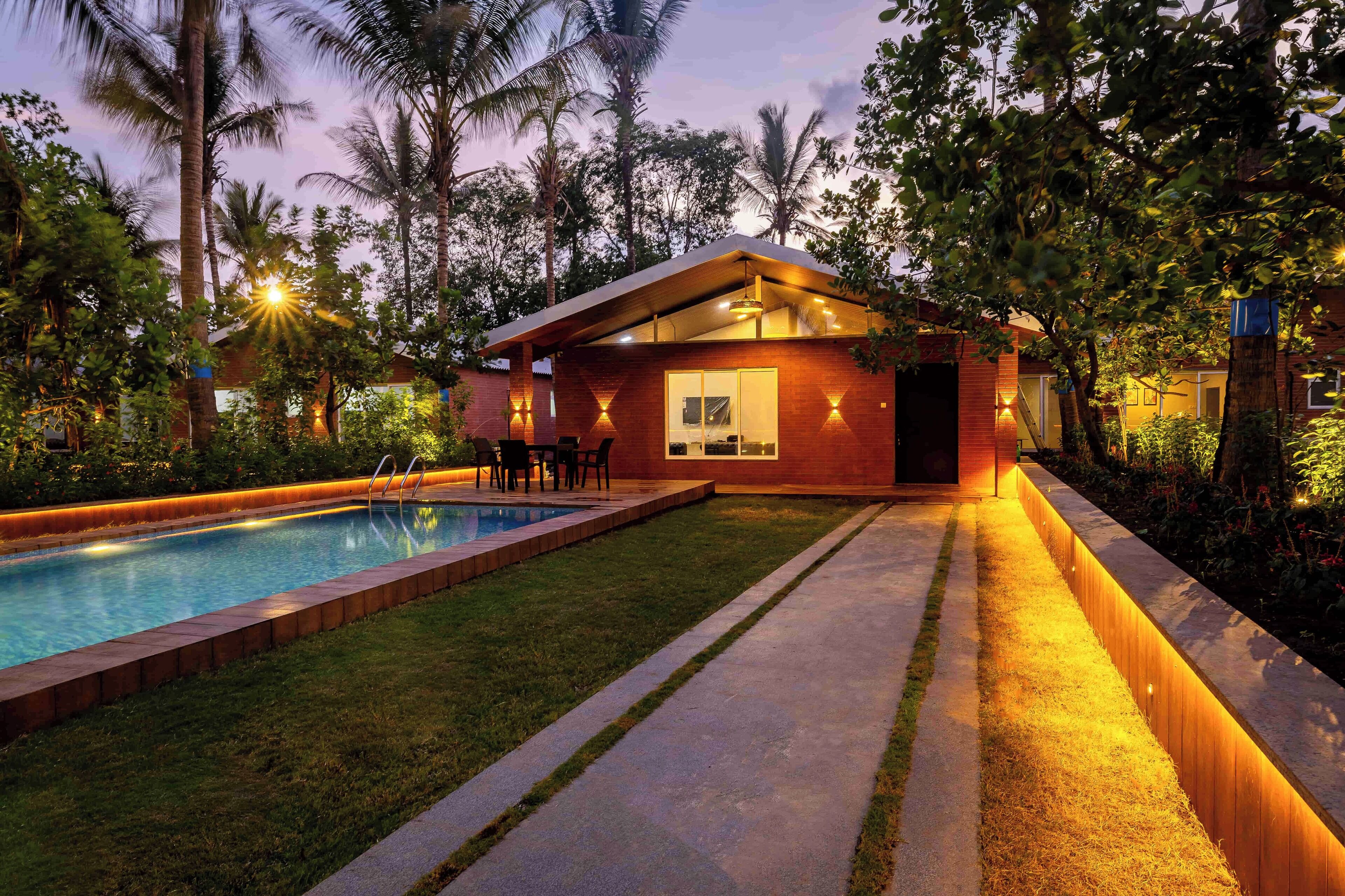 A modern house with a swimming pool, surrounded by lush greenery and palm trees.