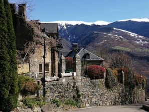 Ein Steinhaus mit einem geneigten Dach, einem kleinen Balkon und einem Blumenkasten.
