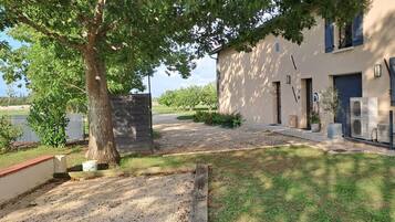 A residential property with a paved driveway, a stone wall, and a grassy lawn.