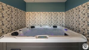 Un bain à remous doté d’un panneau de commande, entouré de carreaux aux motifs géométriques.