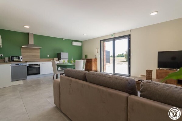 Een moderne woonkamer met een bank, een televisie en een keuken met een eettafel.