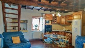 A cozy kitchen with wooden cabinets, a dining table with chairs, and a blue sofa. - La Grande Ourse - Montespan (Montespan)
