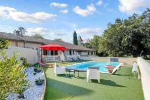 Ein Garten mit Schwimmbad, Kunstgrasanlage und weißem Zaun.
