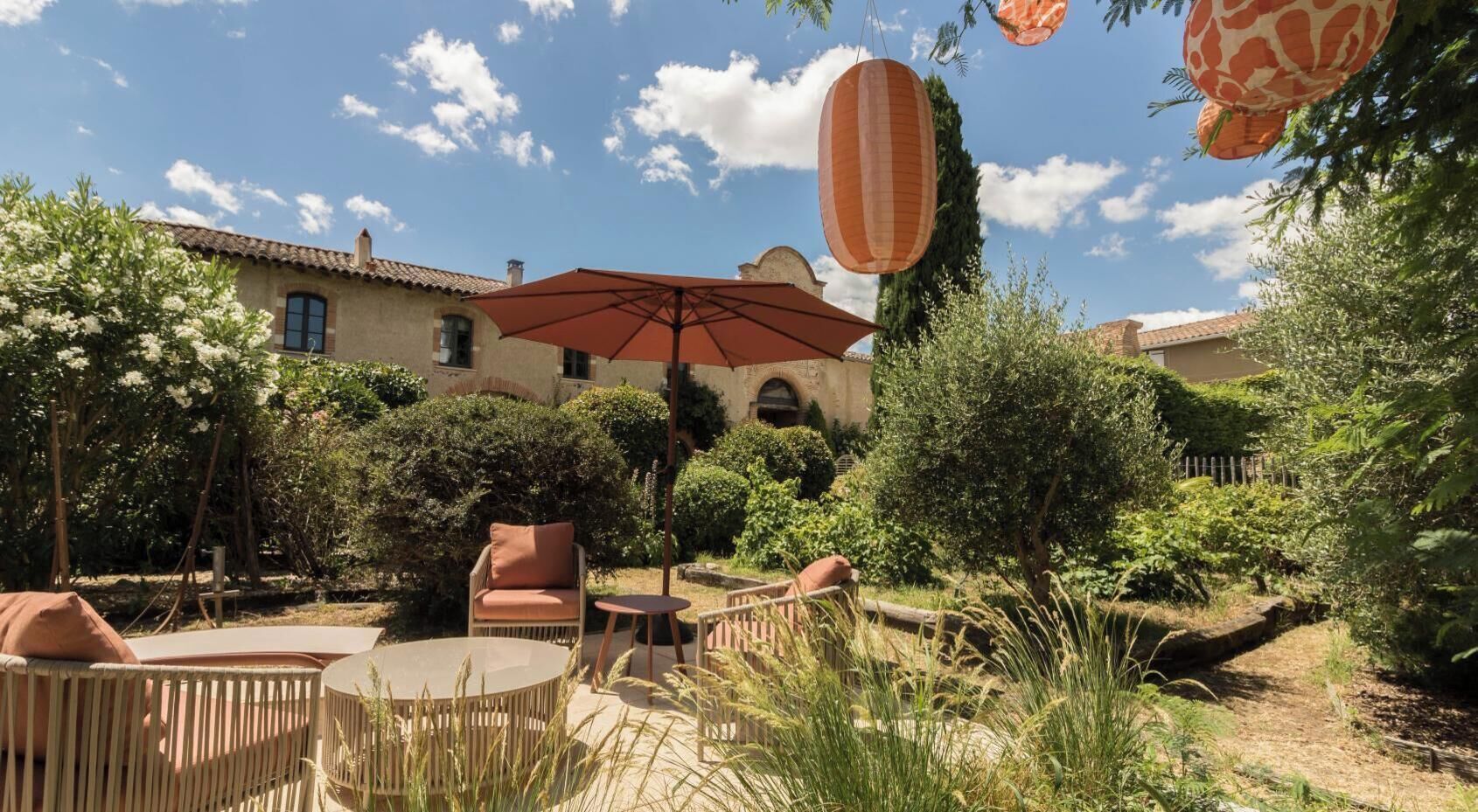 A patio area with outdoor furniture, a large umbrella, and a building in the background.