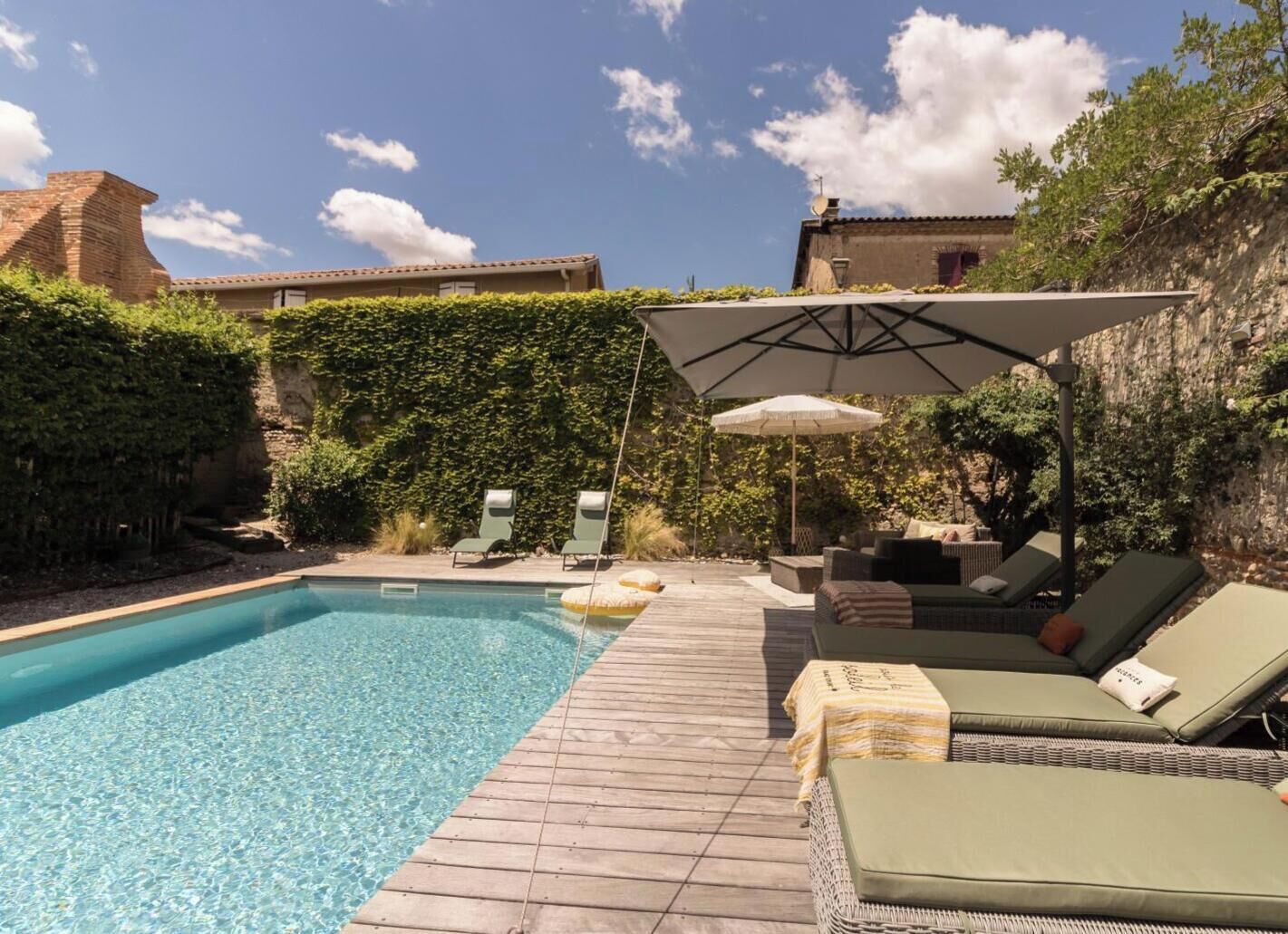 Une piscine avec des chaises longues et une terrasse en bois.