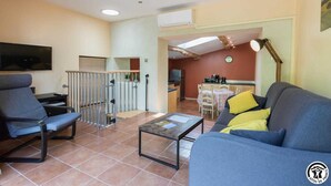 A living room with a sofa, a coffee table, and a TV. There is a balcony with a railing and a view of the outside. - Las Brancas - Cessales (Cessales)