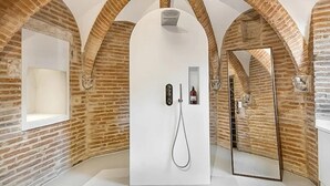 A modern bathroom with a shower, a mirror, and a bottle of shampoo.