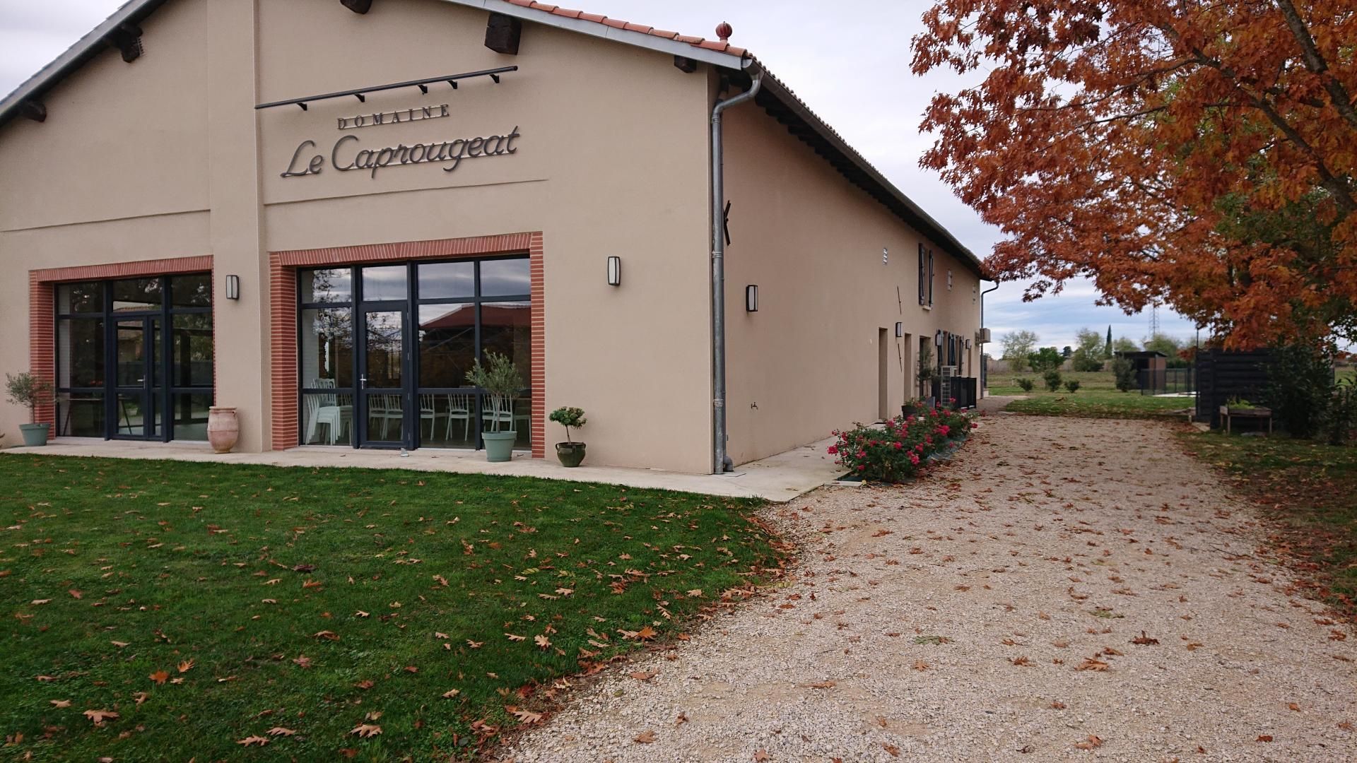 Rakennuksen edessä on kyltti, jossa lukee »Domaine Le Caprougeat», ja sorapäällysteinen ajotie johtaa sisäänkäynnille.