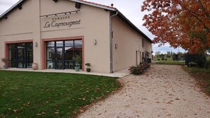 Een gebouw met een bord waarop 'Domaine Le Caprougeat' staat, en een grindpad dat naar de ingang leidt.