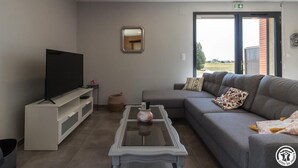 A modern living room with a flat-screen TV, a sofa, a coffee table, and a small decorative vase. - Domaine le Caprougeat - Chic countryside (Daux)
