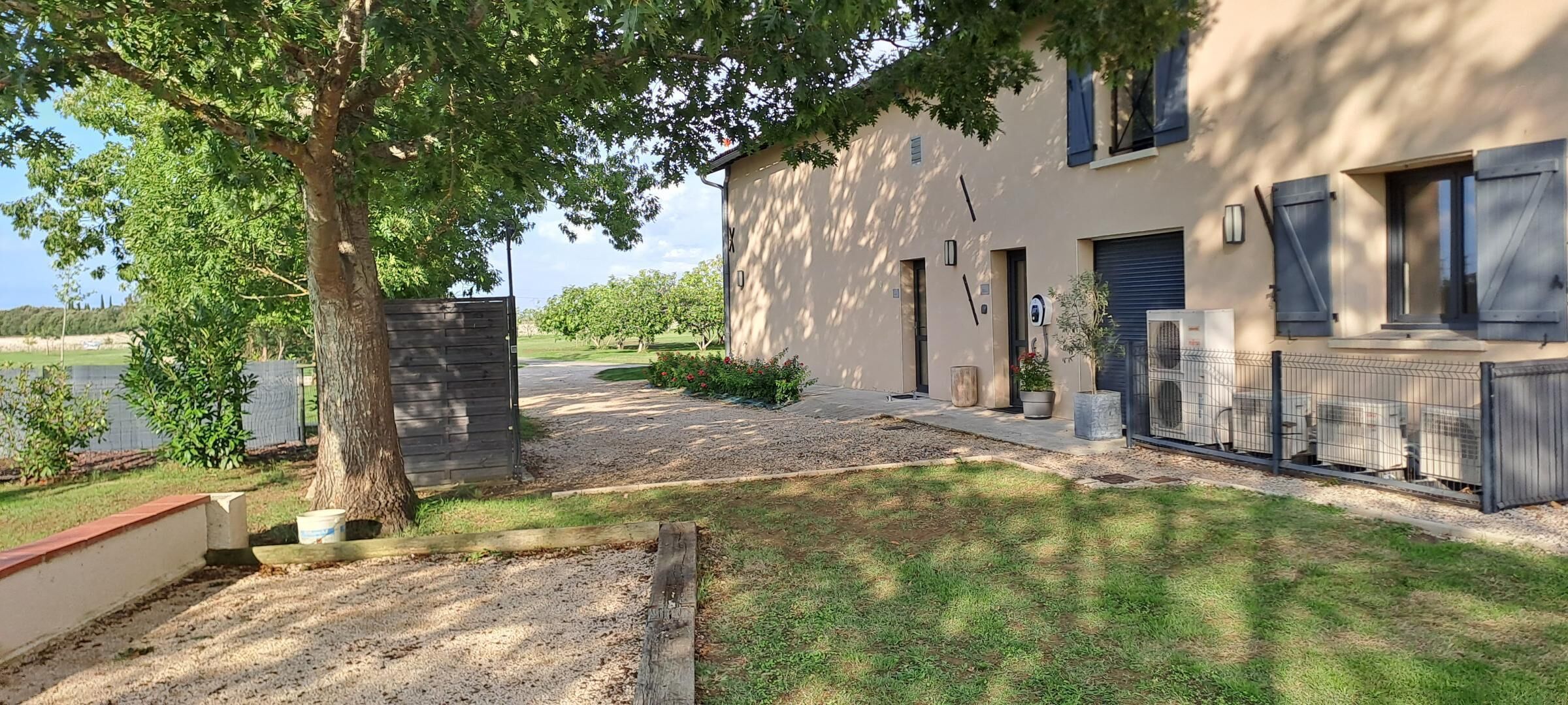 A residential property with a paved driveway, a stone wall, and a grassy lawn.