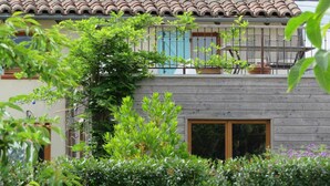A two-story house with a tiled roof, wooden balcony, and a garden in the foreground. - Gîte du Pradel - Saint-Jory (Saint-Jory)