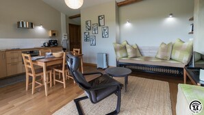 A cozy living area with a sofa, a dining table with chairs, a black leather chair, and a small round table. - Gîte du Pradel - Saint-Jory (Saint-Jory)