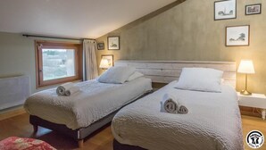 A hotel room with two beds, a window with a view, a radiator, and a lamp on a bedside table. - Gîte du Pradel - Saint-Jory (Saint-Jory)