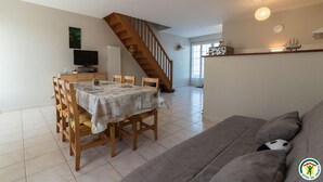 A spacious living area with a dining table, a sofa, and a staircase leading to another level. - Quioussac - Montégut-Lauragais (Montégut-Lauragais)