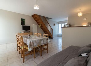 Een ruime woonkamer met een eettafel, een bank en een trap naar een ander niveau.