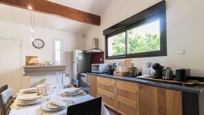 Une cuisine avec des meubles en bois, un four à micro-ondes, un réfrigérateur et une fenêtre donnant sur un paysage verdoyant.