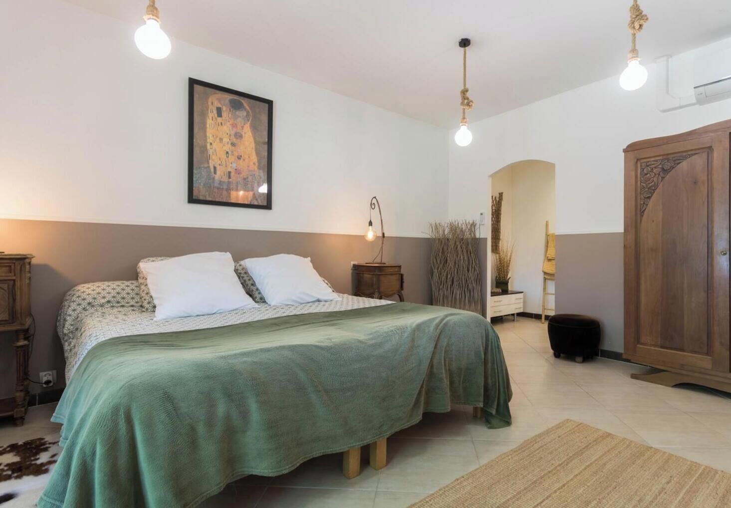 Un dormitorio con cama, mesita de noche, lámpara y un cuadro en la pared.