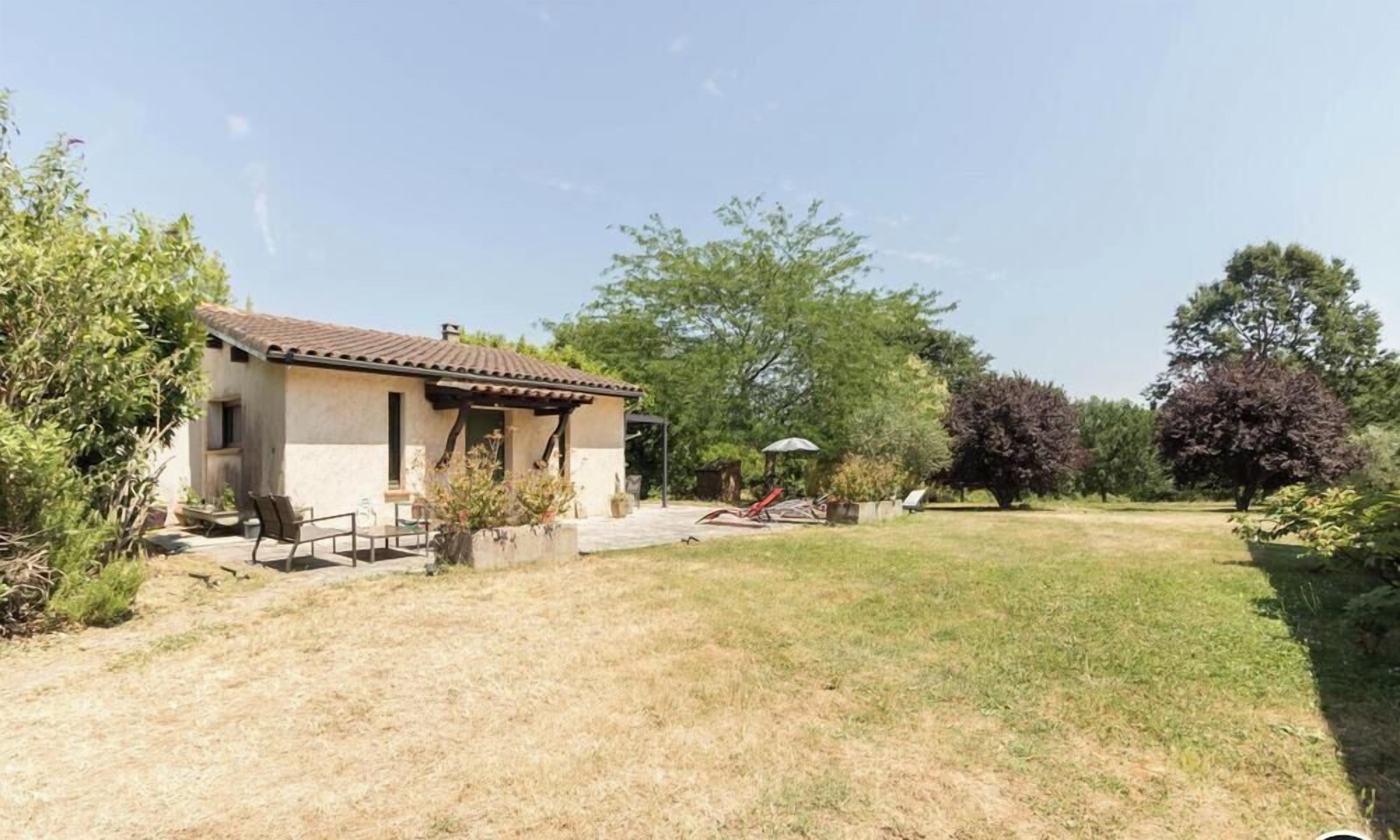 Einbungalow mit gefliesenem Dach, einer Veranda und einem kleinen Garten.