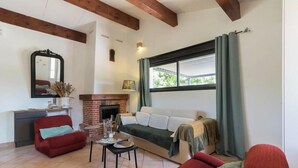 Un salon avec une cheminée, un canapé, un fauteuil rouge et une table à manger.
