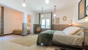 Une chambre à coucher avec un lit, une fenêtre, une chaise et un luminaire suspendu.