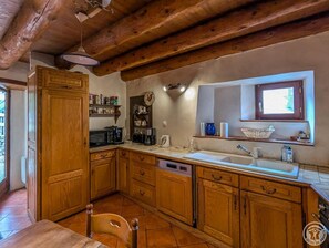 A rustic kitchen with wooden cabinets, a built-in microwave, and a window above the sink.