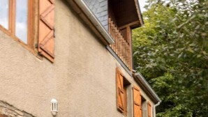 Un bâtiment rustique en pierre, doté de volets en bois et d’un balcon.