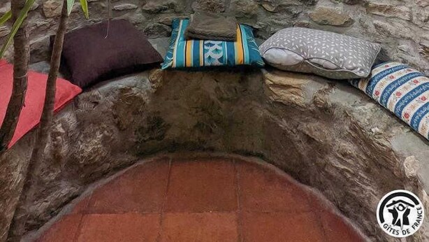 Une pièce chaleureuse avec un mur en pierre, une lucarne et un coin salon agrémenté de coussins.