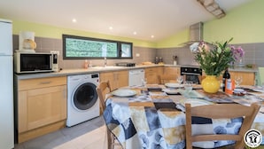 Een kleine keuken met een wasmachine, magnetron en een eethoek met een tafel gedekt voor twee personen.