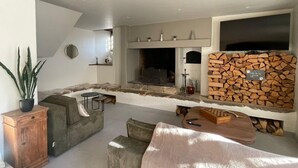 Una sala de estar moderna con chimenea, pared de piedra y televisor.