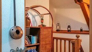 Ein rustikales Zimmer mit einem Holztisch, Bücherregalen und einer Treppe.