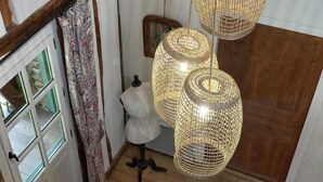 A room with a wooden floor, a white door with glass panels, and a patterned curtain. There are three wicker lampshades hanging from the ceiling. - Chez Pailhas - Régades (Régades)