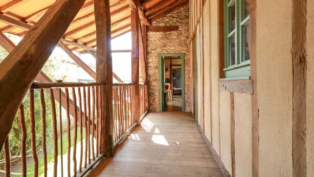 A wooden covered porch with a stone wall and a door leading to an interior room. - Chez Pailhas - Régades (Régades)
