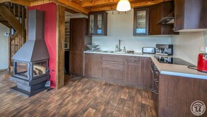 Une cuisine avec des poutres en bois, une cuisinière encastrée et des meubles de couleur sombre.
