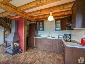 A kitchen with wooden beams, a built-in stove, and dark cabinets.