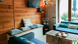 Une pièce chaleureuse avec des murs en bois, une télévision, une cheminée et un canapé agrémenté de coussins.