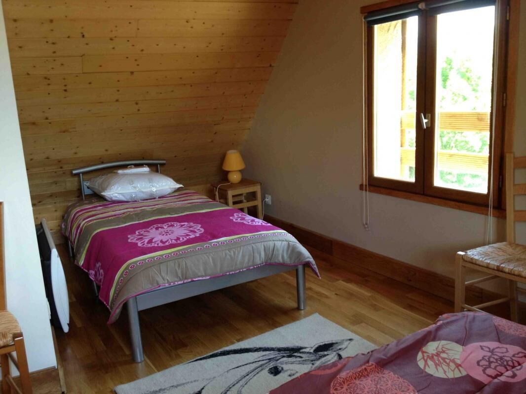 Ein Schlafzimmer mit Bett, Nachttisch, Sessel und Fenster.