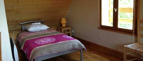 Ein Schlafzimmer mit Bett, Nachttisch, Sessel und Fenster.