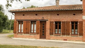 Un bâtiment en briques, doté d’un toit en tuiles, de volets en bois et de fondations en pierre.